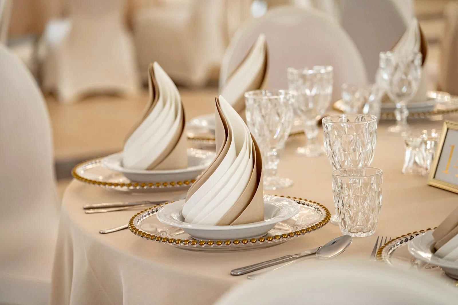 Feiertisch mit elegant gedecktem Geschirr und Kristallglas in heller Dekoration für Hochzeiten und festliche Anlässe.